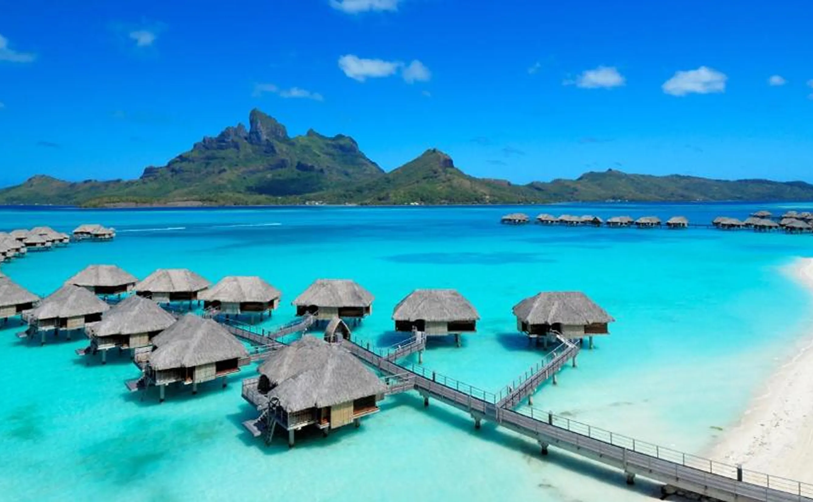 Overwater bungalows on turquoise lagoon with mountain