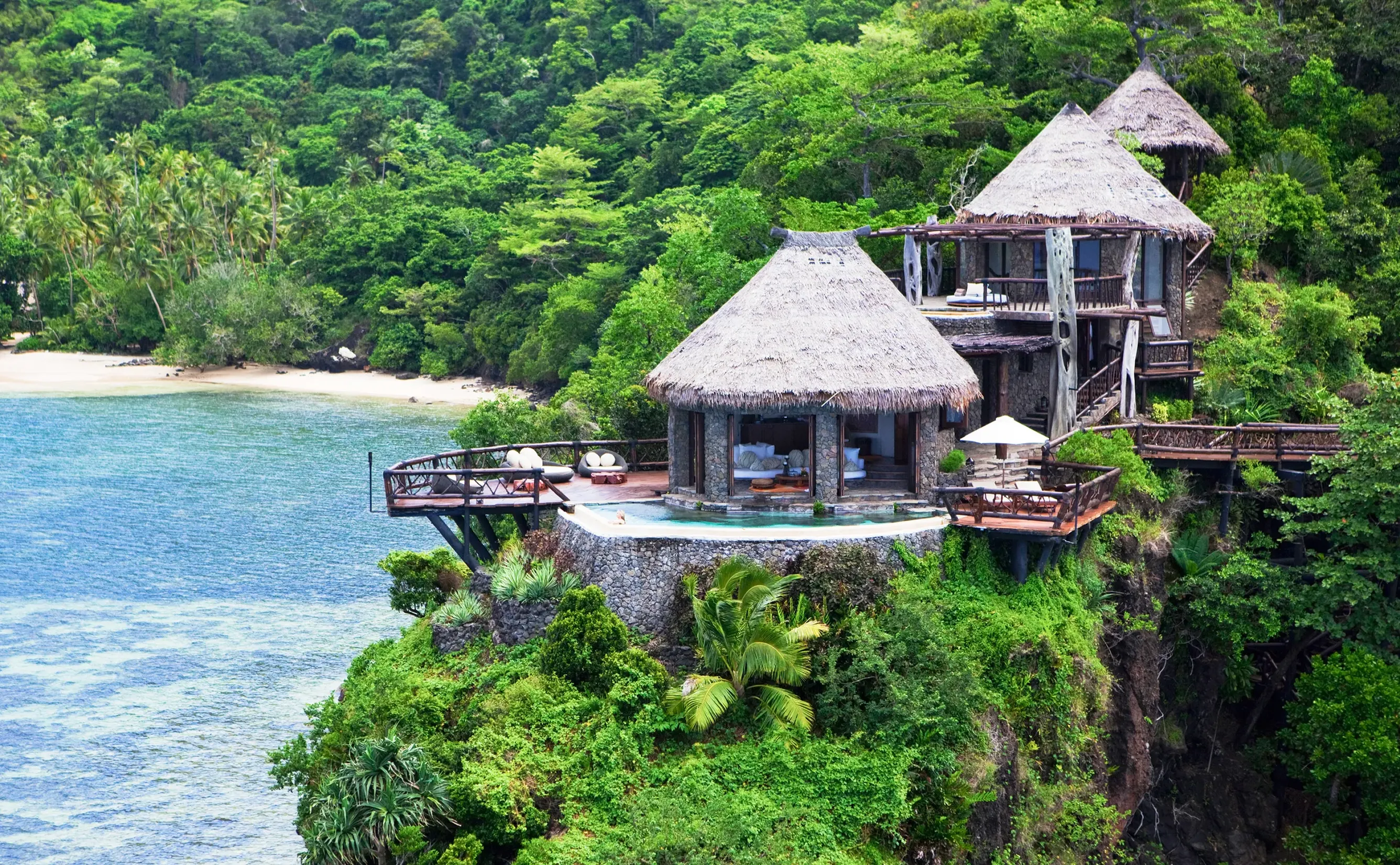 Cliffside thatched roof villas overlooking turquoise ocean