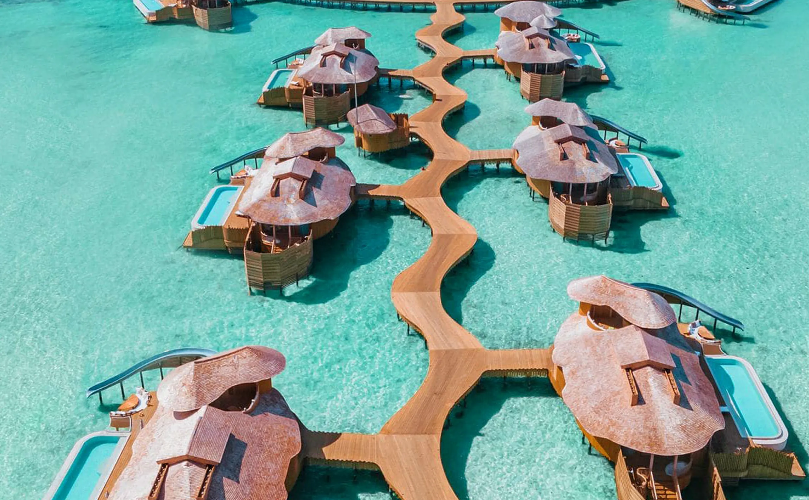 Aerial overwater bungalows with winding wooden boardwalk