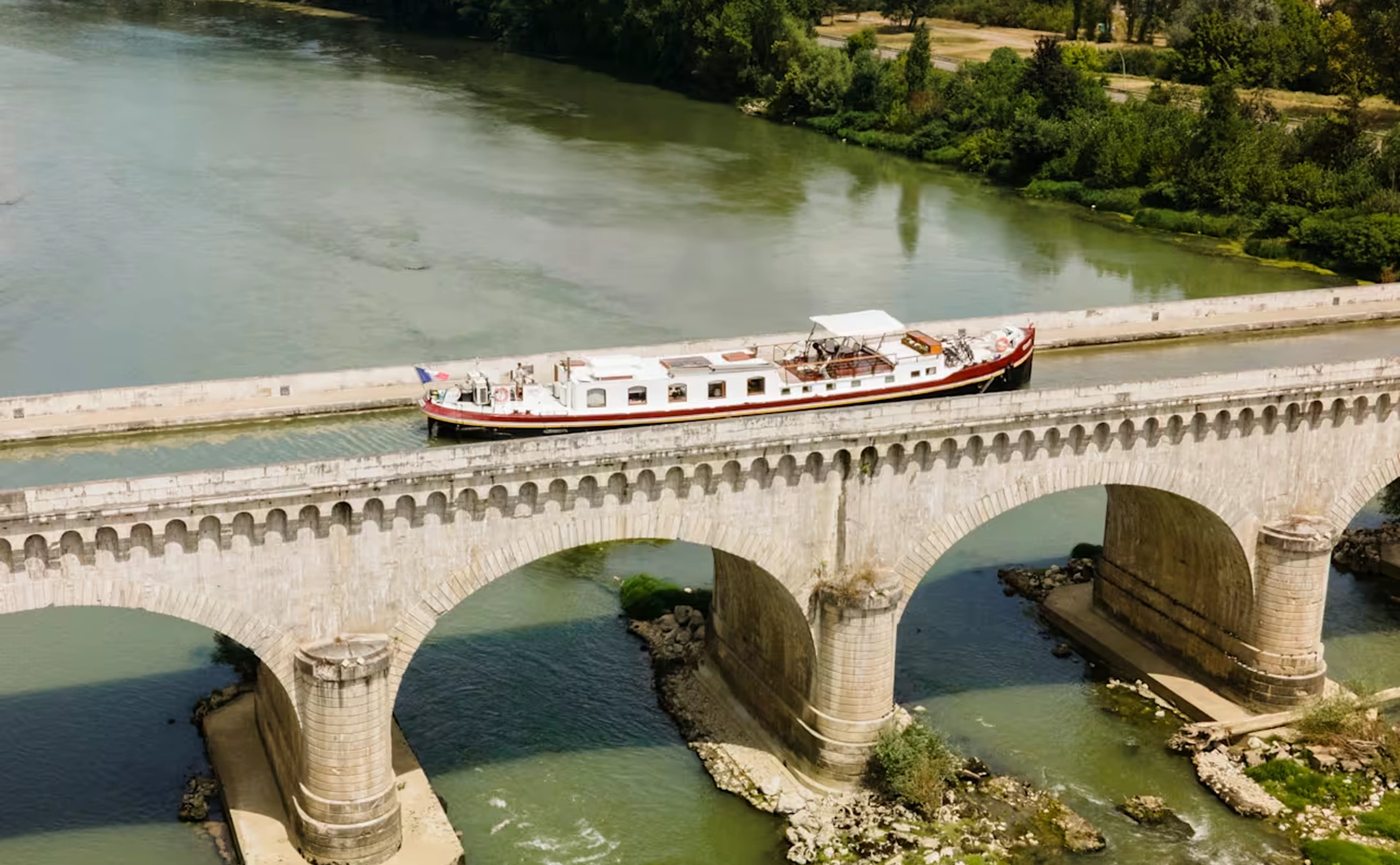River cruise boat crossing stone arch bridge